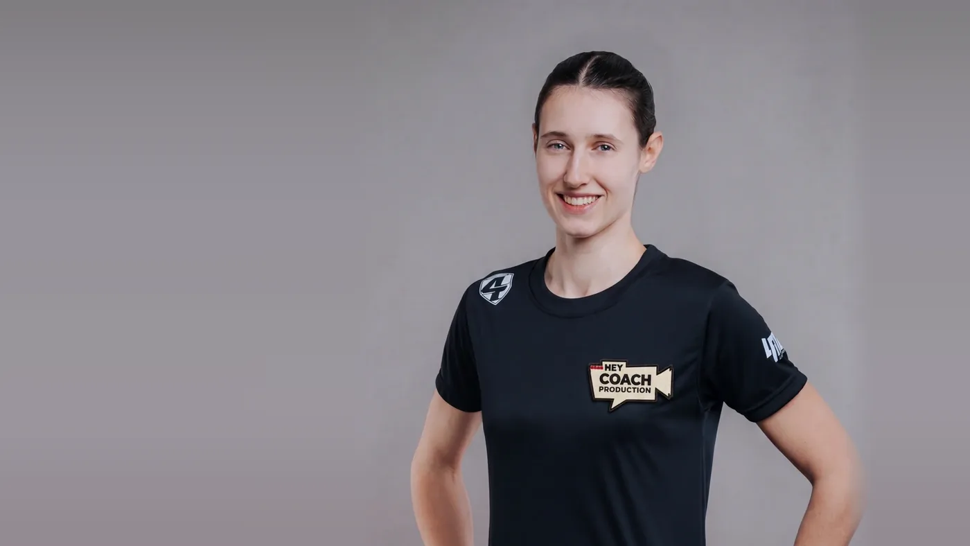 Jana, ISKA-Weltmeisterin und Trainerin bei Hey Coach, im Hey-Coach-Shirt vor grauem Hintergrund